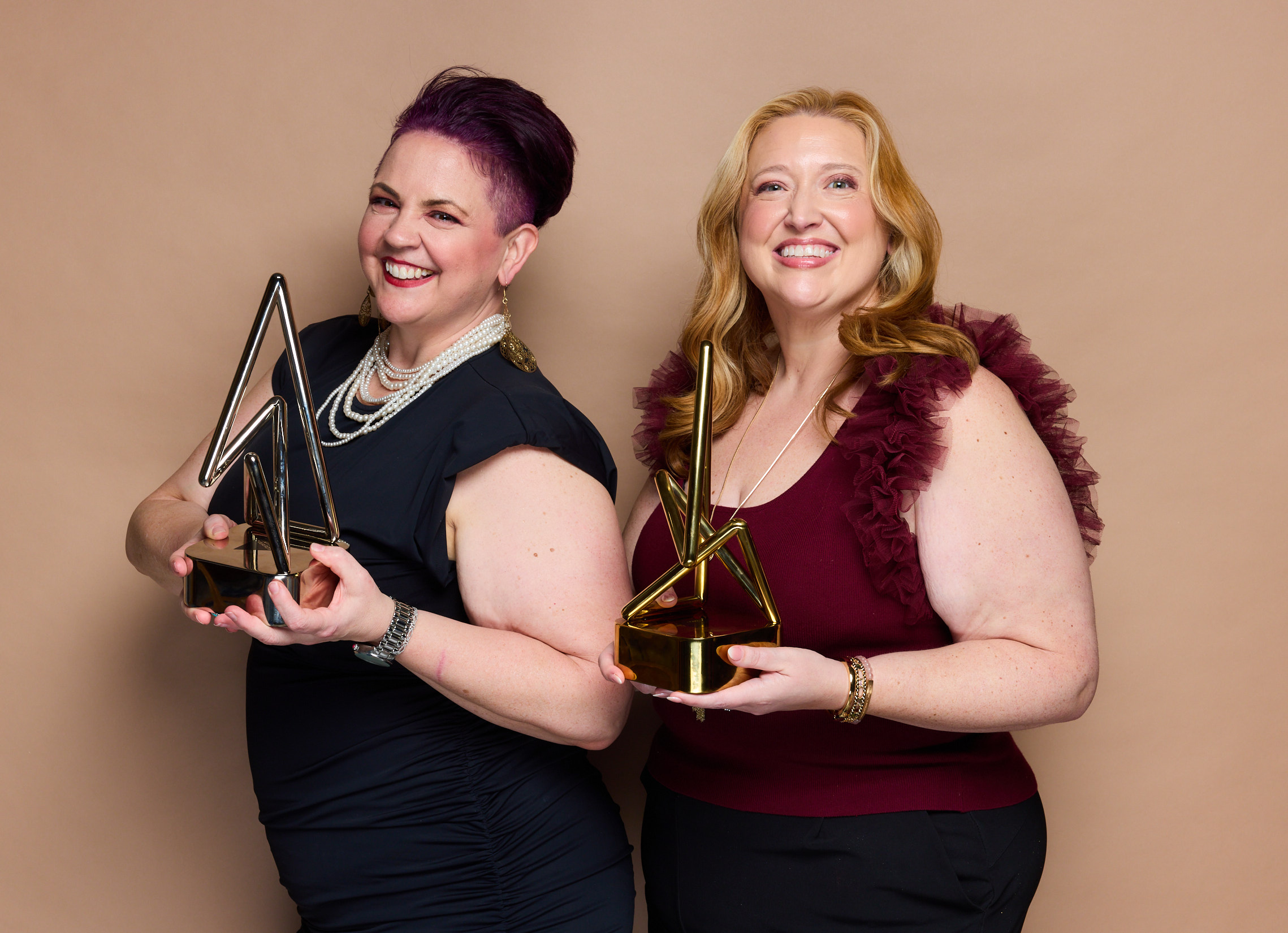 Kat Carter and Kim Carlos holding their Anthem Awards